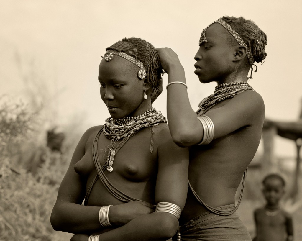 Ethiopia, Omo Delta.  A Dassanech girl braids her sister's hair at her village in the Omo Delta. Source: John Warburton-Lee / Getty